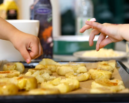 Children’s hands can be seen above a tray of potatoes