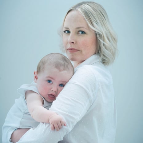 Leah McLaren standing and holding a wriggly eight-month-old Frank, both facing the camera, both with bright blue eyes
