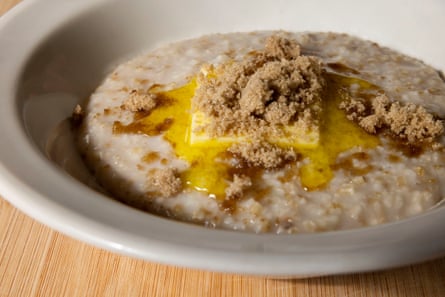 A bowl of creamy porridge topped with butter and brown sugar.