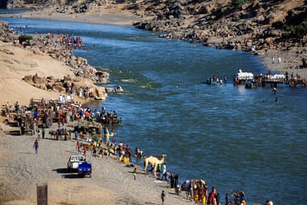 Ethiopian refugees who fled the fighting in the Tigray region gather on the banks of a border river with Sudan on 22 November.