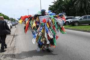 Um homem vestido com lixo plástico caminha por uma rua em Abidjan, Costa do Marfim