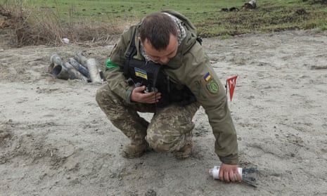 A military sapper picks up an unexploded part of a cluster bomb left after Russia’s invasion in the Kyiv region.