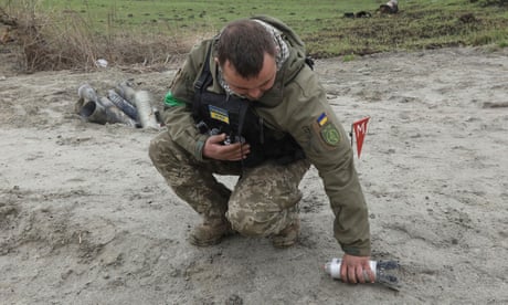 Military sapper picks up an unexploded part of a cluster bomb left after Russia's invasion in Kyiv region