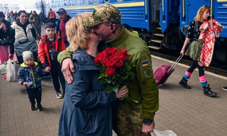 A woman embraces her husband, a Ukrainian serviceman, as he arrives by train in Lviv