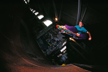 A person skateboarding in a dark building with small windows