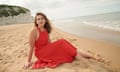 Daisy Buchanan  sitting on the beach in a red dress
