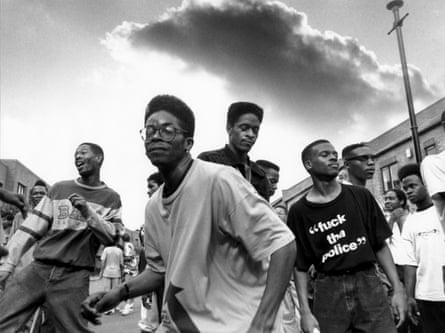A black and white photo of young men dancing in the street at the Notting Hill carnival in 1993