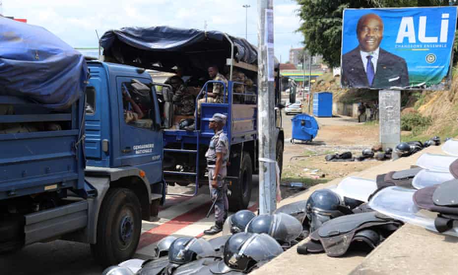 Gabonese security forces alongside poster of Ali Bongo