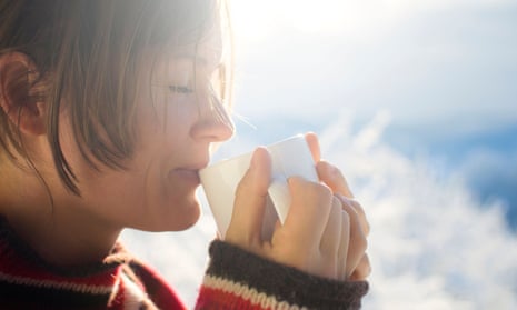 Young woman drinking hot drink outside on a sunny cold winter morning.