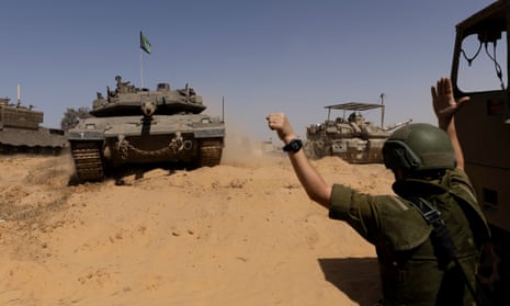An Israeli soldier directs a tank near the border with  southern Gaza after several Israelis were wounded when mortar fire struck the Kerem Shalom 