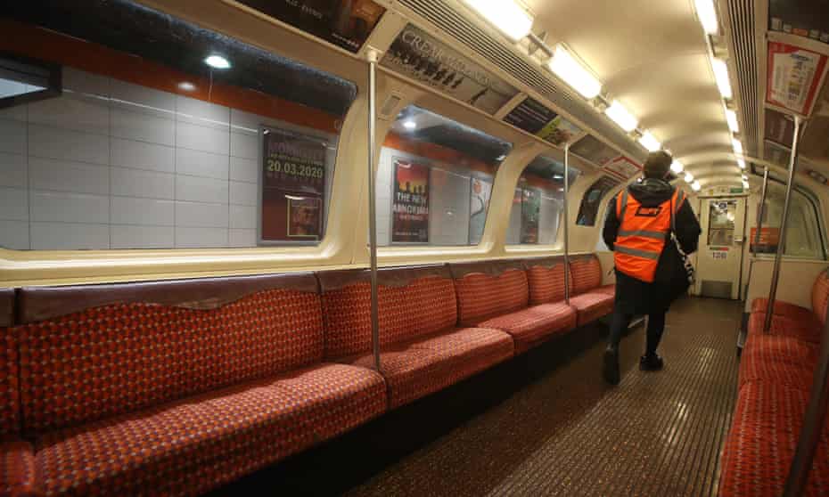 A member of staff in a hi-vis vest walks through an empty train
