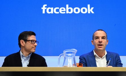 The two men sitting in front of a facebook logo. There is a jug of water between them