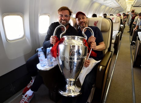 Jürgen Klopp holds the Champions League trophy with Mike Gordon, the FSG president, on the plane back from the 2019 final win in Madrid