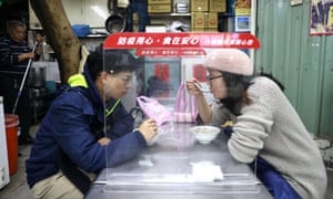 A couple eat behind a plastic shield to prevent the spread of the coronavirus at a market in Taipei, Taiwan, 6 January 2021.