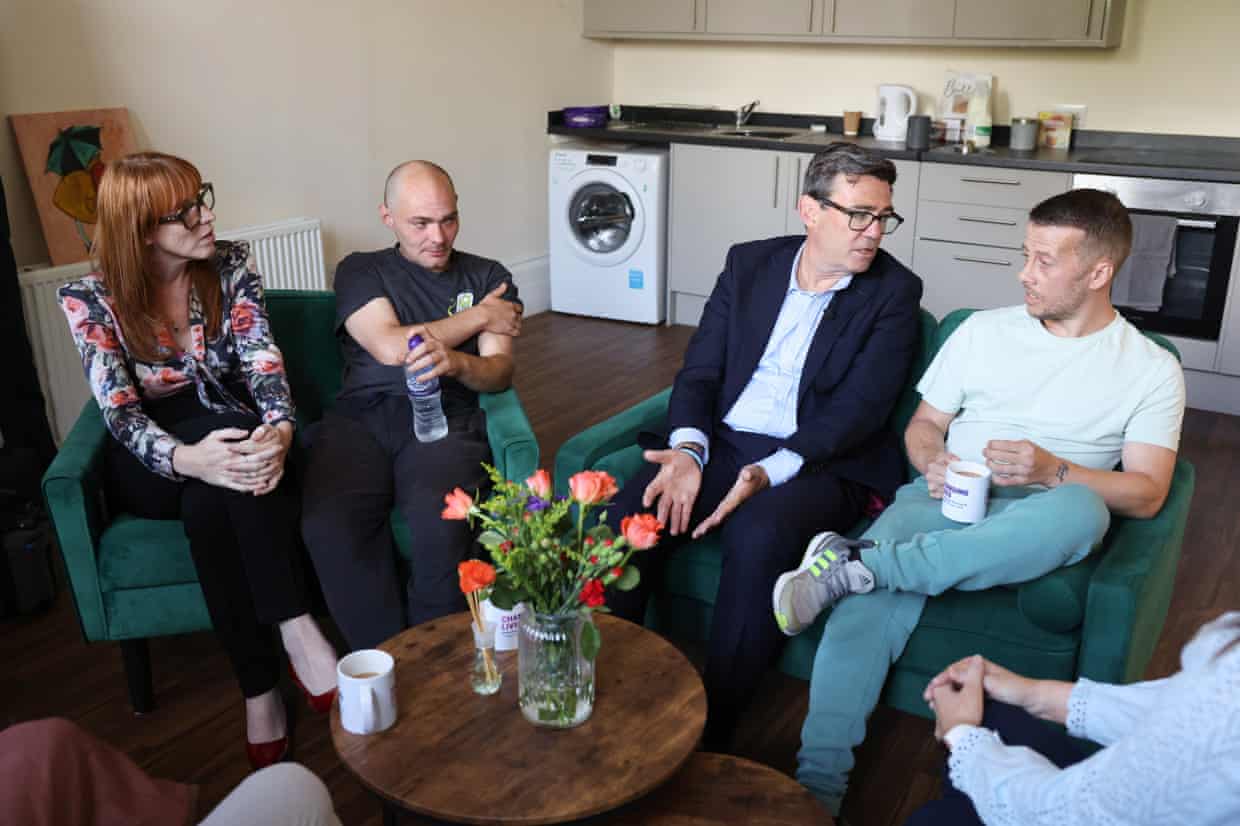 Angela Rayner and Andy Burnham with two men in the kitchen of a homeless accommodation centre.