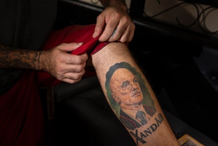 A man shows a tattoo of a bald man on his leg