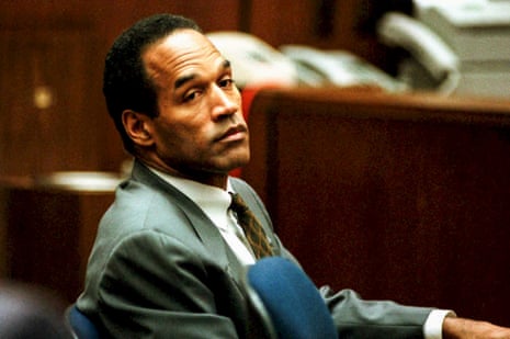 a man in a grey suit and tie looks to the side while sitting in a courtroom