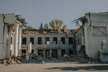 The front of a bombed out building with the roof particularly damaged