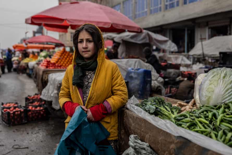 A girl, 10, with plastic bags in a Market.