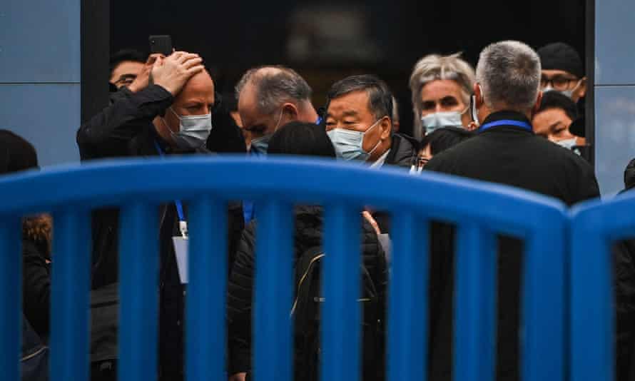 people in masks behind a security barrier