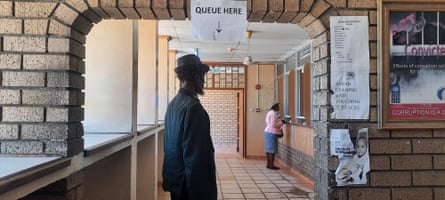 An African man in a trilby waits inside a border post office