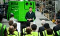 Rishi Sunak standing in front of a green cherrypicking machine and addressing an audience of people in hi-vis vests
