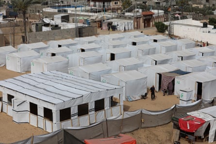 Rectangular white tents lined up on sandy ground