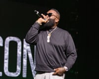 Man on stage sings into microphone with one hand in pocket