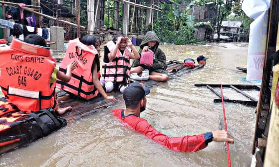 The Philippine coast guard evacuates residents from flooded homes on a makeshift raft in Capiz province
