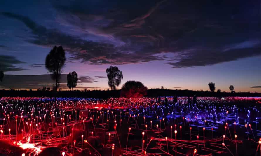 Red and blue lights illuminate the Field of Light at sunset near Uluru