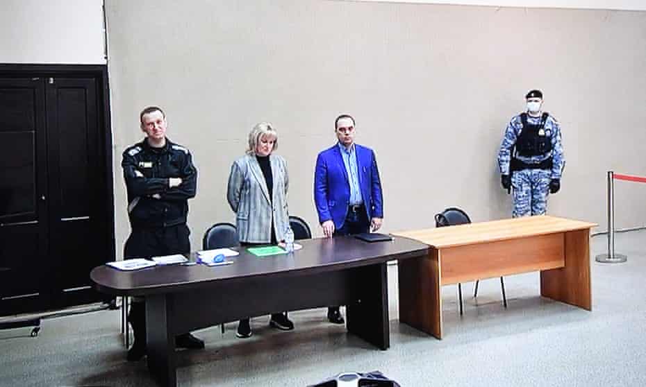 Alexei Navalny, left, with his lawyers and court security staff, as he hears the accusations against him.