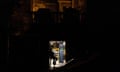 Security guard sits in a lit doorway during a partial electricity blackout in Kyiv.