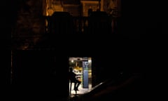 Security guard sits in a lit doorway during a partial electricity blackout in Kyiv.
