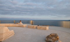 A platform with stone blocks overlooks the ocean and an overcast sky