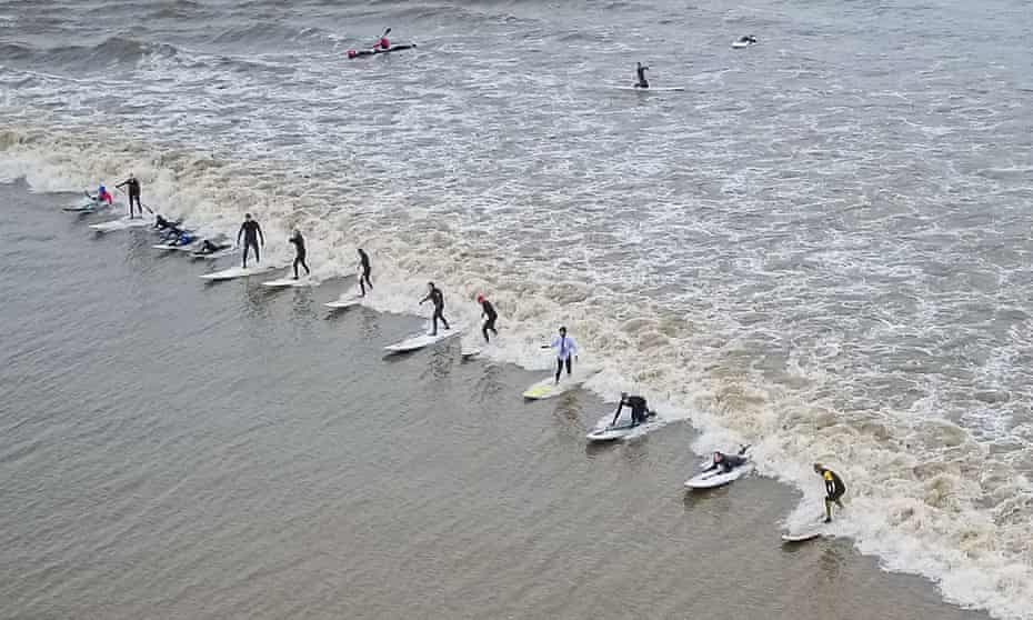 Surfers in Gloucestershire ride a wave formed in the Severn estuary, which has the second largest tidal range in the world.