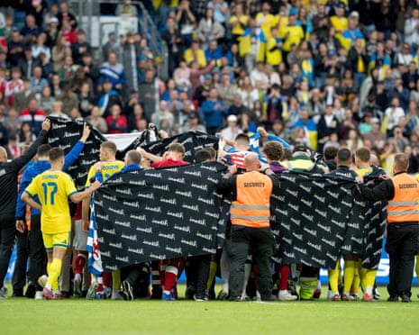 Players and staff hold screens around Christian Eriksen as he receives treatment on the pitch in Odense.