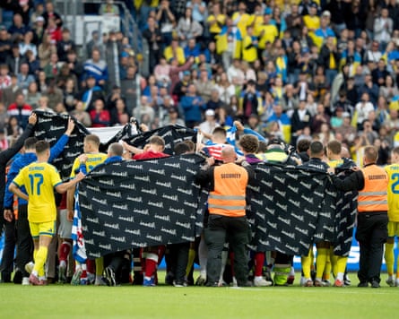 Denmark’s and Ukraine’s players accompany Christian Eriksen to a waiting ambulance during the international friendly soccer match.