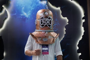 A man stands with what looks like an old-fashioned deep sea diving helmet on his head