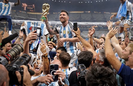 Lionel Messi of Argentina shows off the trophy to fans as he is carried around the pitch after the World Cup final.