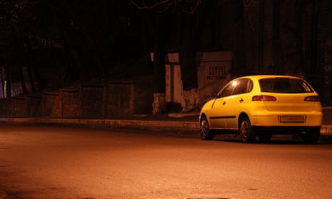Yellow car in empty night street and cosy light spot on asphalt road.