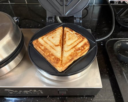 Half of the Dualit is in frame, open with a golden brown toasted sandwich on its plate.