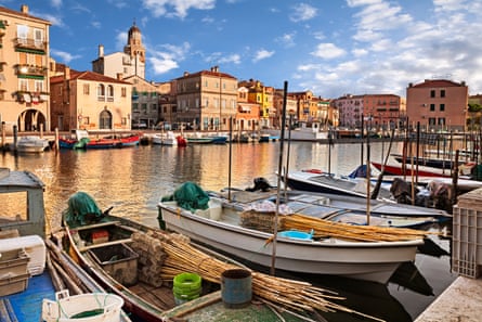 Landscape of canal with fishing boats and ancient buildings in Italy