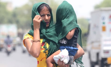 A woman covers her baby with a cloth during a hot afternoon on the outskirts of New Delhi, India in May.