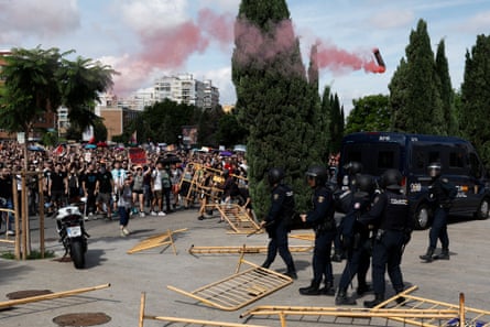 Demonstrators at the head of a huge crowd remove barricades as a small group of police in riot gear gather amid barricades that are lying flat on the ground