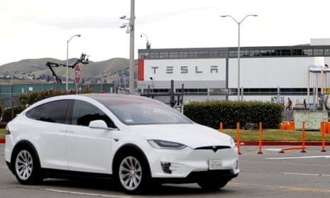 white car with Tesla sign on a building beyond