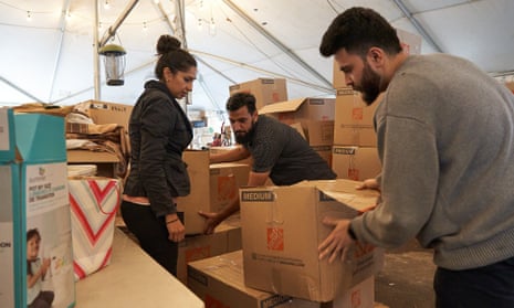 Three volunteers sort boxes of donations to Pakistan flood victims.