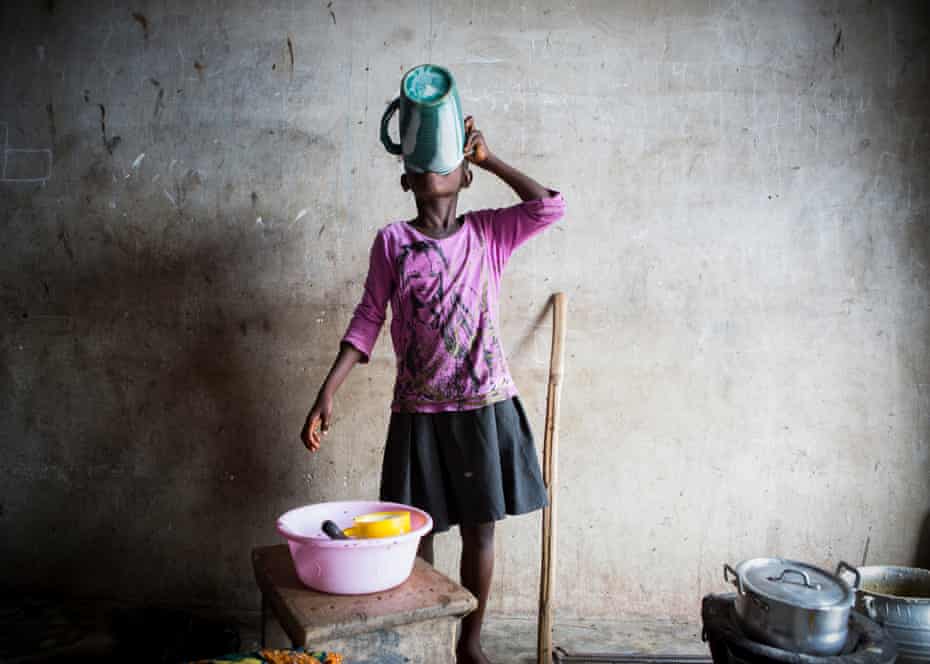 In Nyanyano a young girl prepares food for her family using pots and pans covered in flies