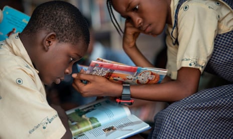 A boy and a girl sit and read books in a mobile library in Lagos.