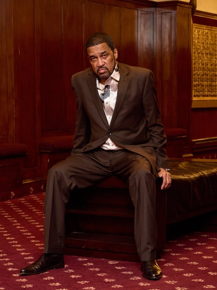 man in a brown suit sitting on a wooden bench