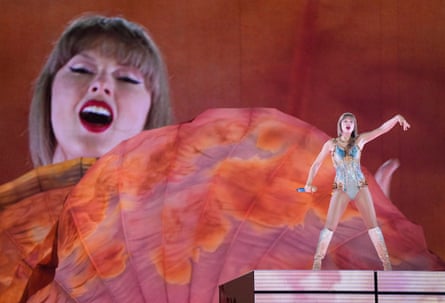 Taylor Swift on stage with a screen behind her showing her big face.